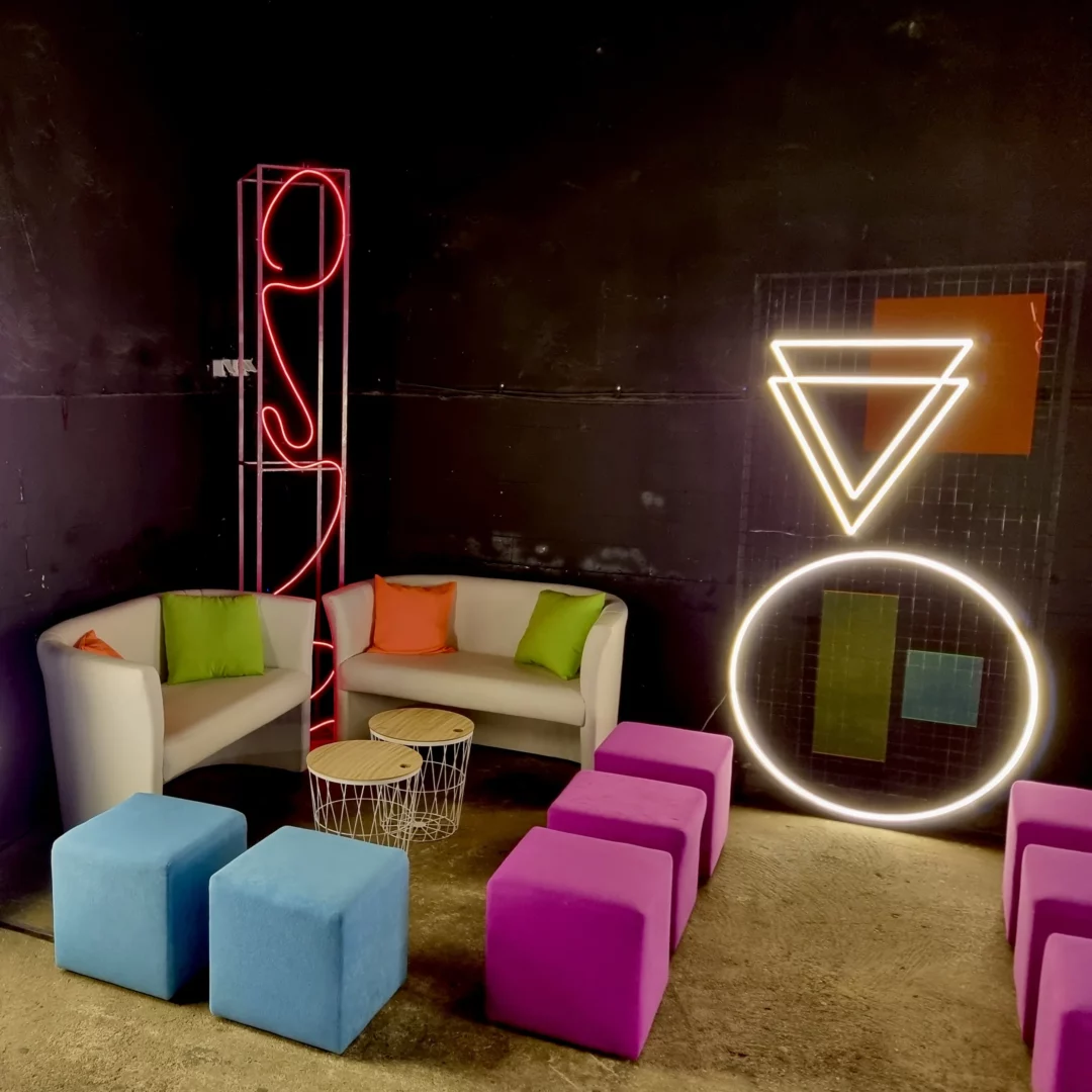Neonowa scenografia z geometrycznymi neonami ożywia eventowy lounge przygotowany przez RENT4EVENTS we Wrocławiu, idealny jako strefa chillout. Białe sofy z kolorowymi poduszkami oraz purpurowe i błękitne kostki siedzące tworzą stylowe miejsce do relaksu - rent4events.pl wypożycz wrażenia, rent4wedding.pl zachowaj wspomnienia. Fot. Kamil.