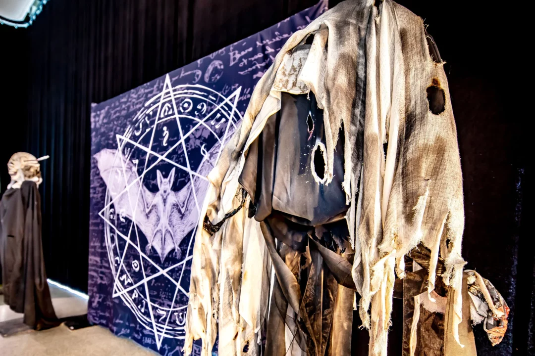 Dekoracja na Halloween z przerażającym manekinem w podartym, zniszczonym kostiumie, stojącym na tle pentagramu i motywu nietoperza. Scenografia w gotyckim stylu, z tajemniczymi symbolami i mroczną atmosferą, idealna na tematyczne eventy we Wrocławiu. Wypożyczalnia Rent4Events.pl oferuje te unikalne dekoracje, które doskonale pasują na wydarzenia o charakterze grozy - rent4events.pl wypożycz wrażenia, rent4weddings.pl zachowaj wspomnienia. Fot. Marek Kaźmierczak @marekkazmierczak.