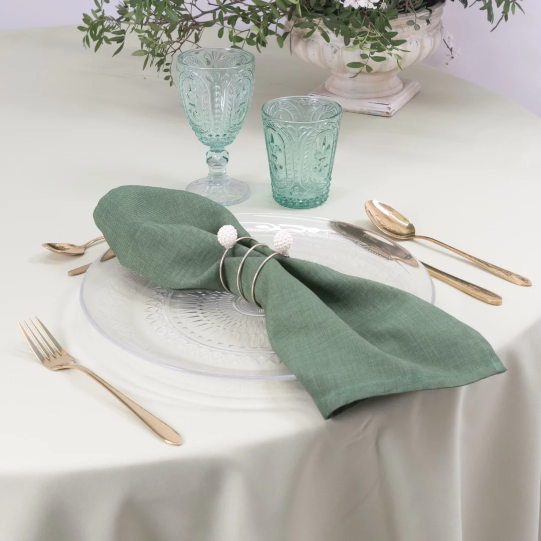 Turkusowy zestaw szklanek z reliefem (szklanka i kieliszek), prezentowany na elegancko nakrytym stole z zieloną serwetą artystycznie złapaną ozdobnym pierścieniem z perełkami i ułożoną na kryształowym, transparentnym podtalerzu w otoczeniu złotych sztućców, odzwierciedla filozofię rent4events.pl. Idealny na śluby i wesela, a także inne eventy we Wrocławiu, dodaje charakteru dzięki rent4weddings.pl - rent4events.pl wypożycz wrażenia, rent4wedding.pl zachowaj wspomnienia.