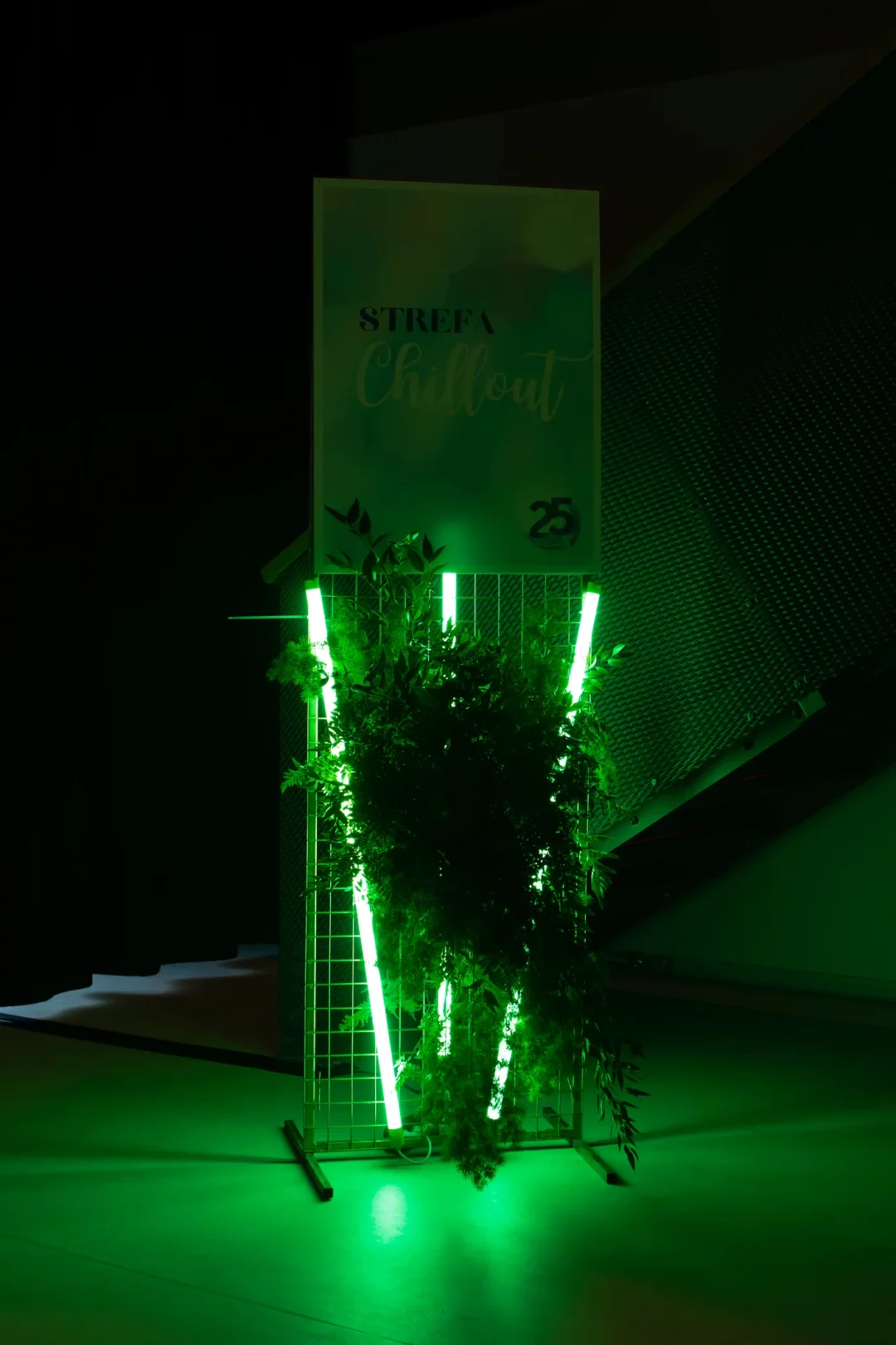 Instalacja eventowa od wypożyczalni rent4events.pl / rent4weddings.pl. Oznaczenie "Strefa Chillout" na wąskiej, złotej kratce z zielonymi neonami LED i naturalną roślinnością. Dekoracja świetnie sprawdzi się na imprezach, gdzie liczy się klimat, detale i estetyka. Wypożyczalnia oferuje pełną obsługę scenografii, od koncepcji po montaż, tworząc magiczne przestrzenie dopasowane do każdego eventu. Wrocław, ślub, wesele, event – dekoracje od rent4events.pl i rent4weddings.pl to gwarancja stylu i jakości - rent4events.pl wypożycz wrażenia, rent4weddings.pl zachowaj wspomnienia. Fot. @karolinakiec_fotografia.