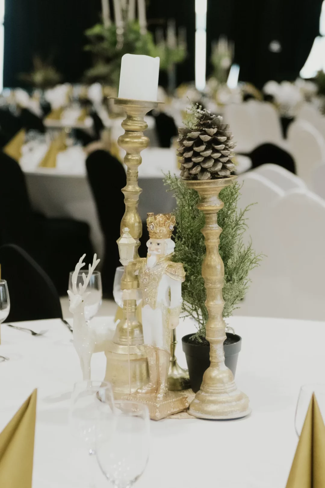Elegancka dekoracja stołu z dziadkiem do orzechów, złotymi świecznikami, szyszką i białą figurką renifera, idealna na zimowe wesele lub event. Stylowa kompozycja ze świątecznym akcentem, doskonała na uroczystości we Wrocławiu i okolicach. Wypożycz wyjątkowe dekoracje z rent4events.pl i rent4weddings.pl dla niepowtarzalnej scenografii - rent4events.pl – wypożycz wrażenia, rent4weddings.pl – zachowaj wspomnienia. Fot. @karolinakiec_fotografia.