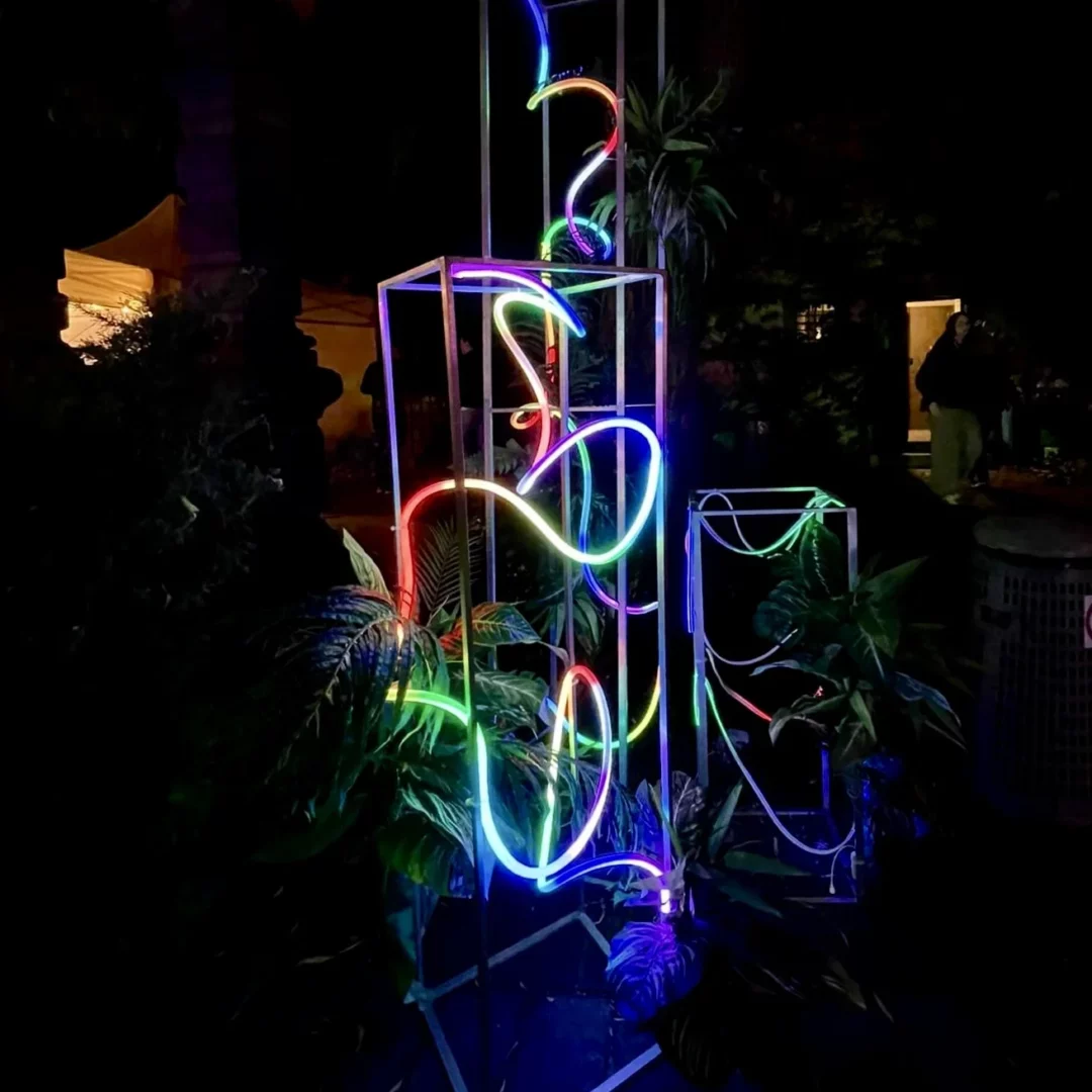 Słupek LED 250 cm, 150 cm i 100 cm. Neon Party. Neon Party. Elegancka neonowa dekoracja składająca się z wysokich metalowych ram słupków wypełnionych wielobarwnymi neonowymi liniami, otoczona tropikalnymi roślinami. Połączenie jasnych kolorów – różowego, niebieskiego, zielonego i czerwonego – z ciemnym, wieczornym tłem tworzy wyjątkowy klimat, idealny na neonowe wesele lub inny event (w plenerze lub we wnętrzach). Ta scenografia świetnie sprawdzi się jako część dekoracji eventowych w klimacie Neon Party dostępnych na wypożyczenie na stronie rent4events.pl i rent4weddings.pl - rent4events.pl wypożycz wrażenia, rent4weddings.pl zachowaj wspomnienia. Fot. Karol.