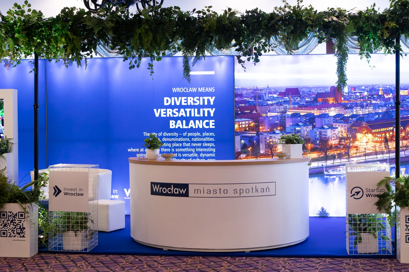 Stoisko targowe z brandingiem „Wrocław miasto spotkań" i „Invest in Wrocław” przygotowane przez wypożyczalnia rent4events.pl i rent4weddings.pl to idealna scenografia na targi czy konferencje. Biała recepcja oraz stelaże z dekoracjami roślinnymi tworzą elegancką i funkcjonalną przestrzeń. Dekoracje i scenografia dostępne w wypożyczalni podnoszą prestiż każdej imprezy. Dla organizatorów eventów i uroczystości ślubnych we Wrocławiu rent4events.pl i rent4weddings.pl oferują kompleksowe rozwiązania - rent4events.pl wypożycz wrażenia, rent4weddings.pl zachowaj wspomnienia. Fot. @karolinakiec_fotografia.