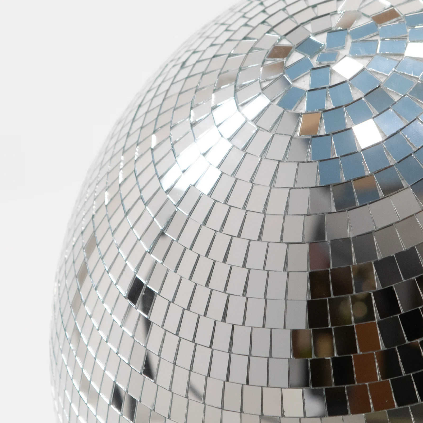 Fragment lustrzanej kuli disco o śr. 50 cm w ujęciu makro prezentuje precyzyjną mozaikę małych srebrnych lusterek odbijających światło i tworzących dynamiczne refleksy. Ta elegancka dekoracja doskonale sprawdza się na eventy i wesela, budując efektowną scenografia świetlną. Produkt ceniony przez branżę wypożyczalnia dekoracji Wrocław, dostępny w ofercie rent4events.pl oraz rent4weddings.pl do realizacji muzycznych i eleganckich aranżacji -rent4events.pl wypożycz wrażenia, rent4wedding.pl zachowaj wspomnienia.