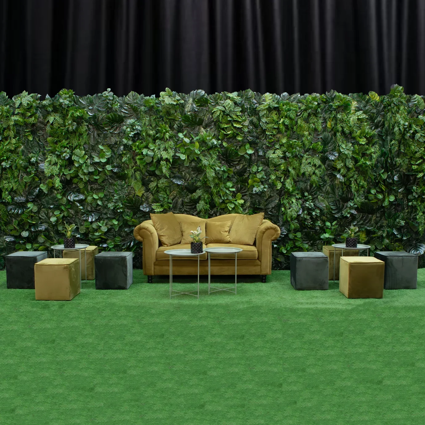 Rozbudowana zielona ściana z tropikalnych liści, paproci i dekoracyjnych pnączy tworzy efektowną scenografię premium z elegancką strefą lounge. Oliwkowa sofa, pufy kubiki w dwóch odcieniach zieleni oraz subtelne oliwkowe stoliki budują komfortową przestrzeń idealną na event, nie tylko w stylu tropikalnym. Wypożyczalnia dekoracji Wrocław rent4events.pl oraz rent4weddings.pl oferuje profesjonalne dekoracje i kompleksową scenografię do organizacji wyjątkowych wydarzeń - rent4events.pl wypożycz wrażenia, rent4wedding.pl zachowaj wspomnienia.