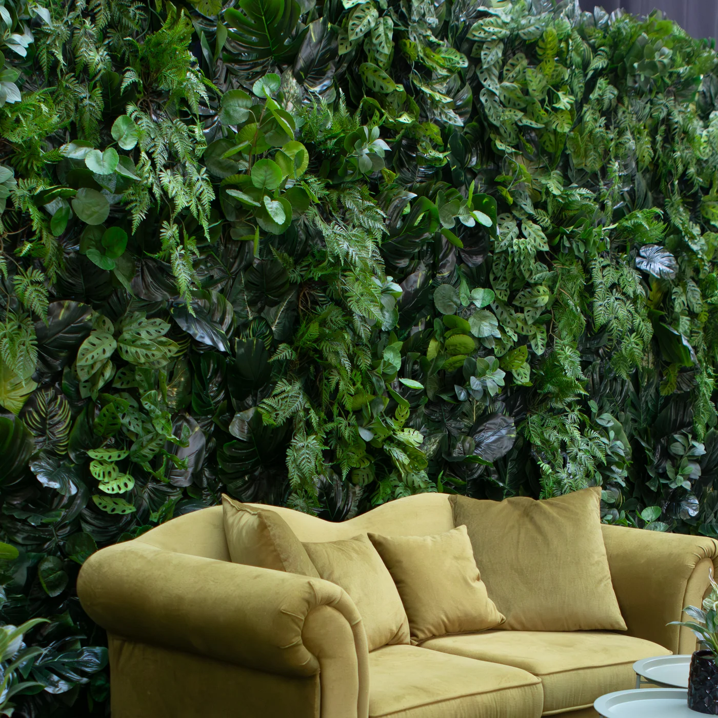 Tropikalna zielona ściana ze sztucznymi, perforowanymi liśćmi monstery, paprociami i dekoracyjnymi pnączami tworzy designerską scenografię z elegancką strefą lounge. Oliwkowa sofa podkreśla ekskluzywny charakter aranżacji, która doskonale sprawdza się podczas ślubu, wesela i eventu. Wypożyczalnia dekoracje Wrocław – rent4events.pl i rent4weddings.pl – zapewnia profesjonalne dekoracje oraz scenografię premium dla wyjątkowych wydarzeń - rent4events.pl wypożycz wrażenia, rent4wedding.pl zachowaj wspomnienia.